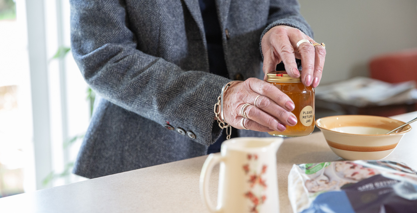 elderly person opening a pot of honey