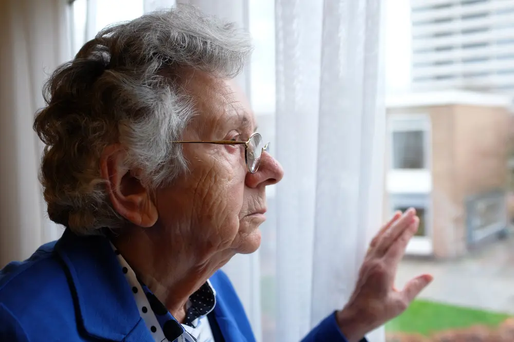 lonely elderly women looking out of window